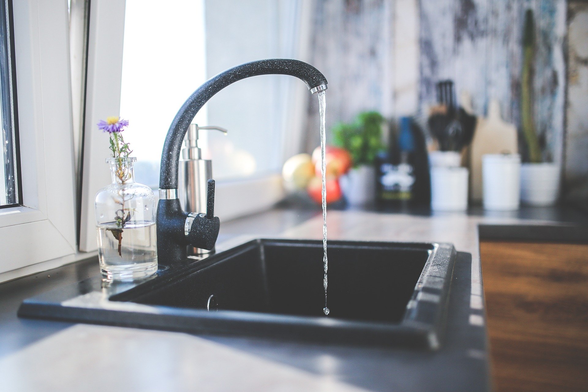 picture of a faucet in someone's kitchen pouring water into a sink to show drinking water contaminants