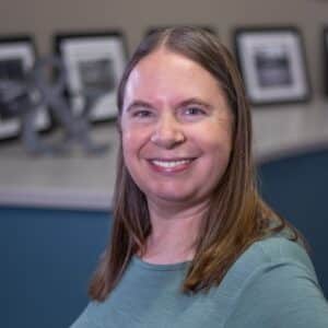 Joanne Theriault standing in office in front of blue wall