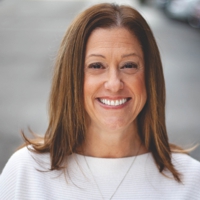 Corporate headshot of Michelle Carrozzella standing outside in a white shirt