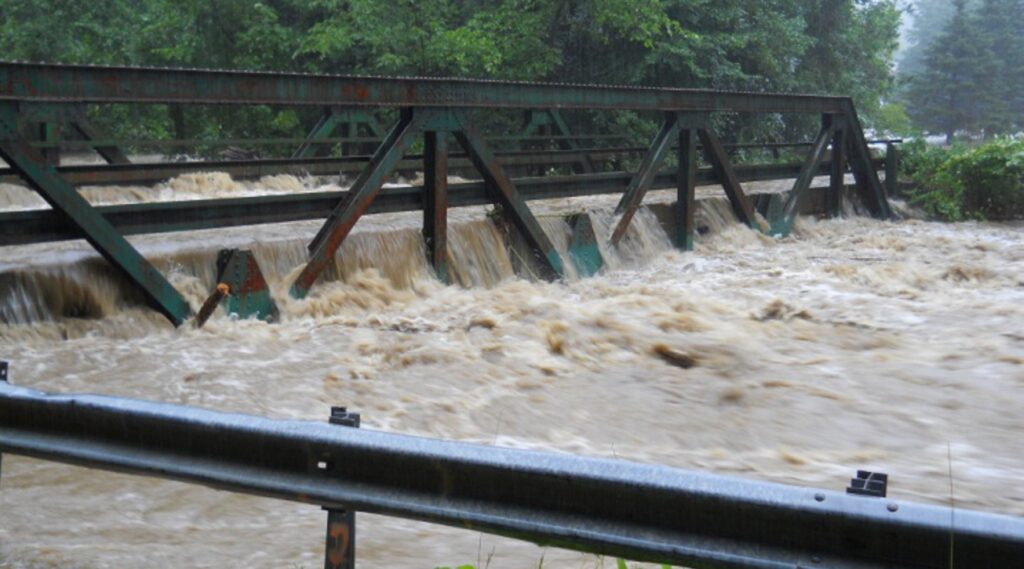 A bridge in Ludlow, Vermont is flooded with brown stormwater.