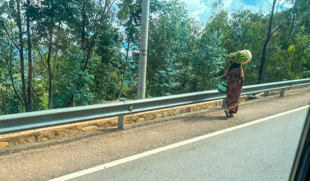 A photo of a woman walking along the clean streets of Rwanda. Her back is to the camera.
