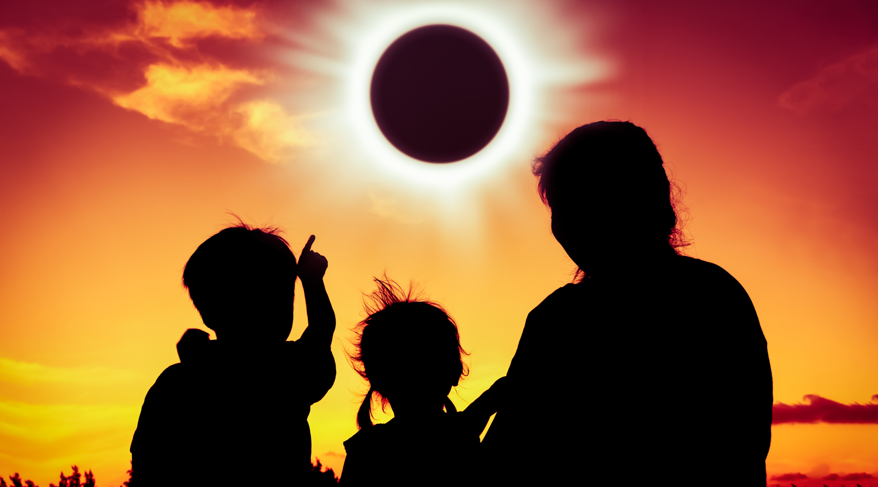 Solar Eclipse featured image with a family looking at the eclipse with an orange sky