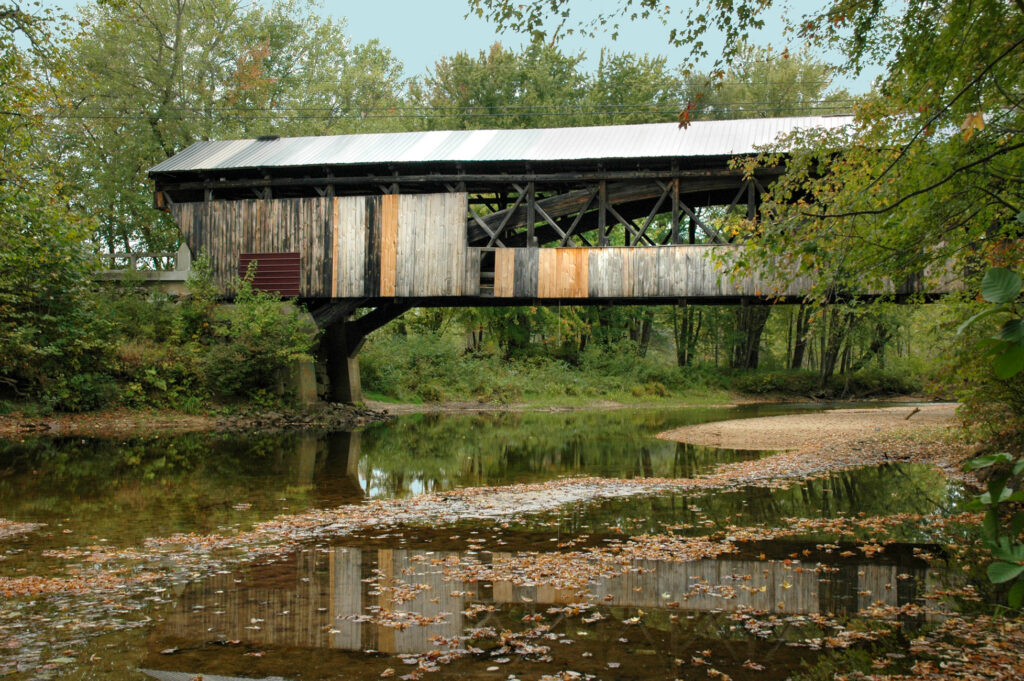 The Whittier Covered Bridge in profile view over in fall. 
