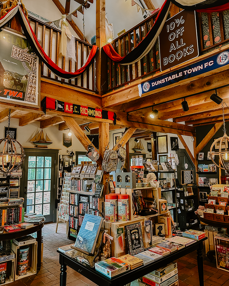 This picture is of the inside of the renovated antique shop that got converted to a cozy bookstore. The inside features high ceilings, books, decorations, and lots of warm toned colors.