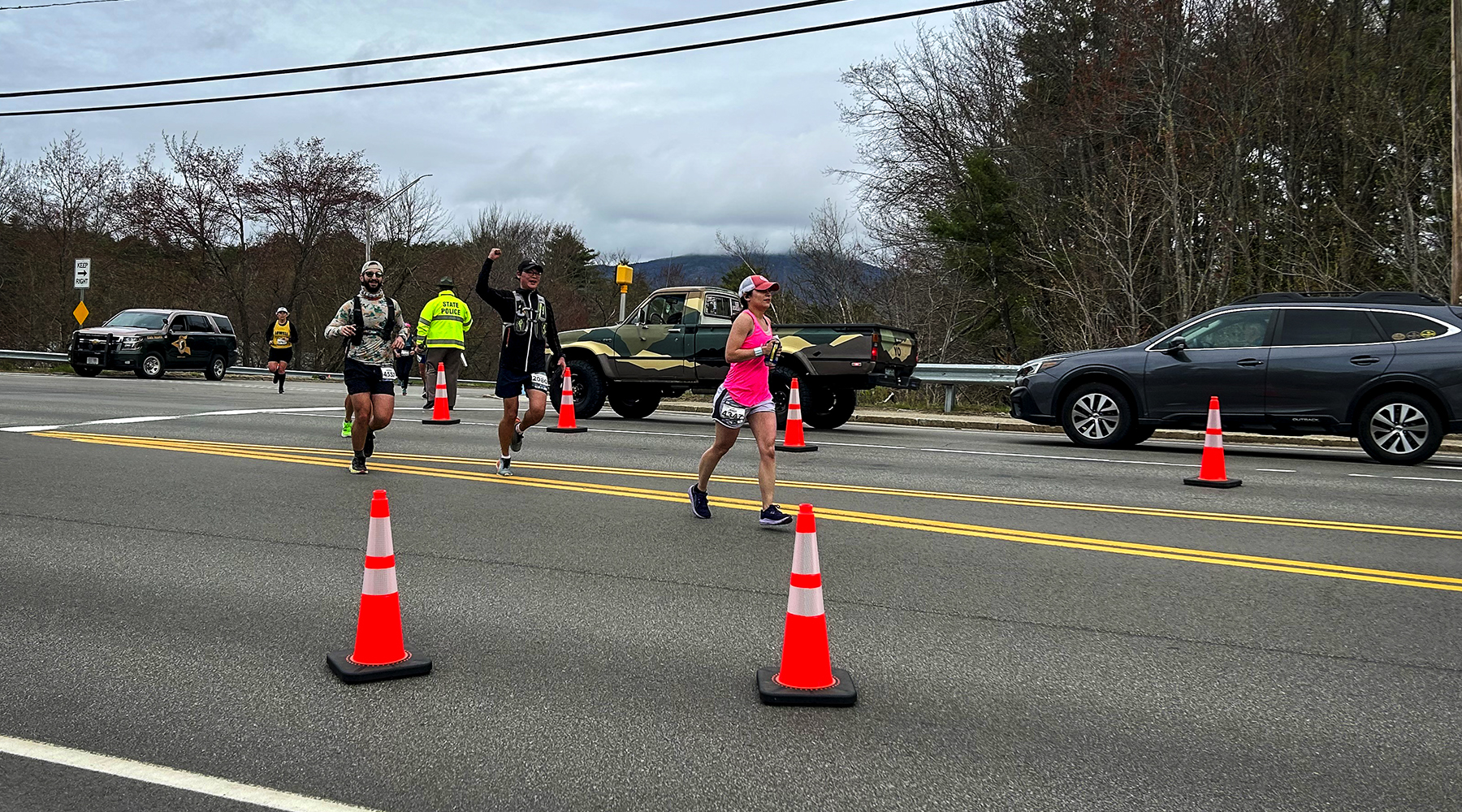 A photo from the Revel Race on the Kancamagus Highway on May 5th where Hoyle Tanner did traffic engineering services. The photo shows runners nagivating orange cones around vehicles.