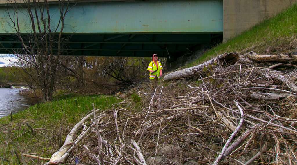 Lynne in a safety vest near a debris pile for a bridge inspection.