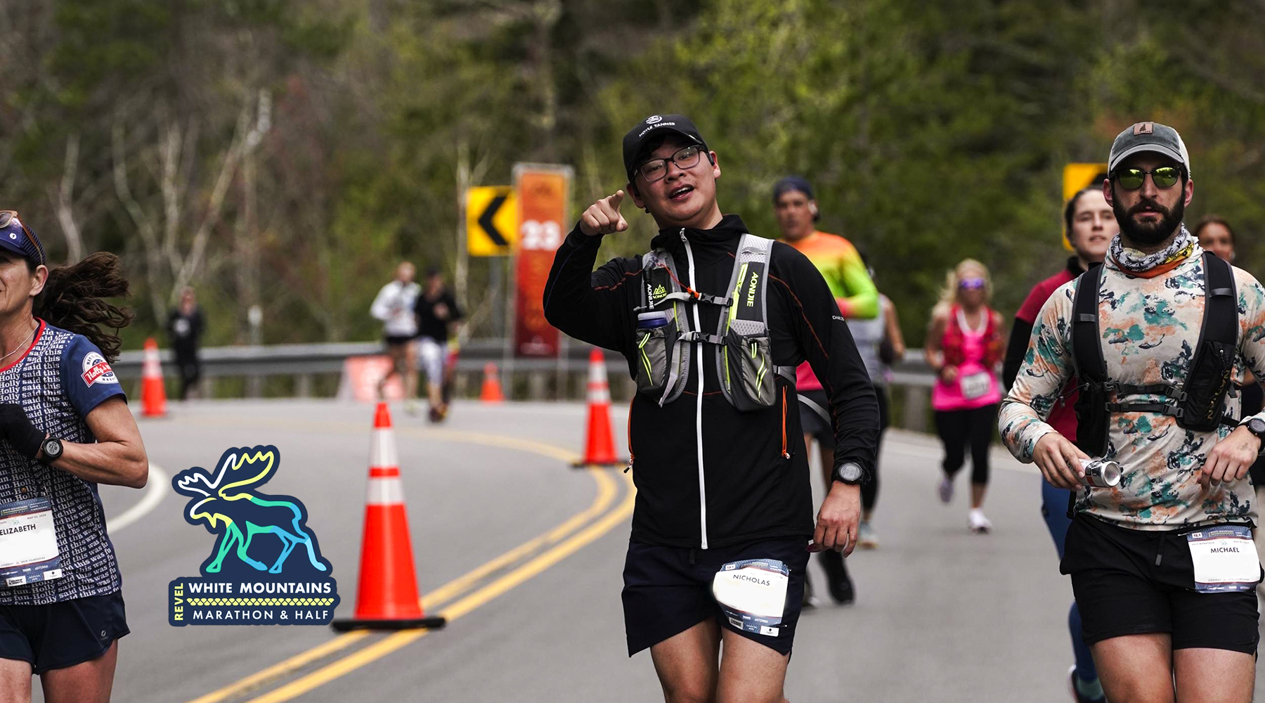 Nick Eagan running during the Revel Marathon race. The photo was taken by the race photographers and he is lifting an arm and smiling in the photo.