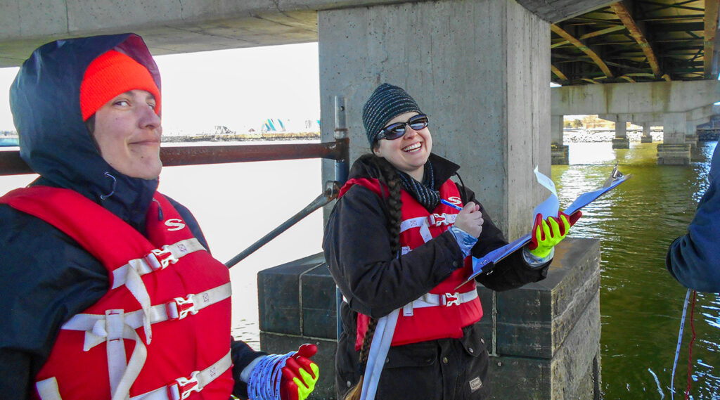 Lynne Sabourin & Kayla Hampe taking depth measurements under a bridge in Portland, ME.