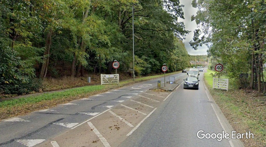 Example of a typical gateway treatment with gatepost signage, a raised median, fencing, colored pavement, and dragon’s teeth road markings. (A6 in Clophill, Bedfordshire, UK – Google Earth)