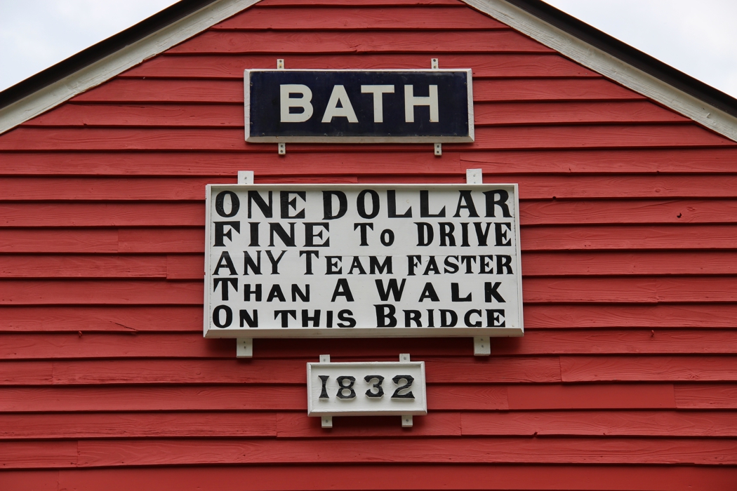 Close up of an old bridge sign that says, "One Dollar Fine to Drive Any Team Faster Than A Walk On This Bridge - 1832."