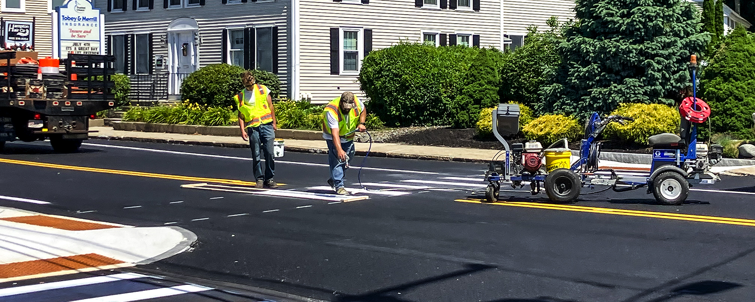 Construction workers are painting fresh lines on the road on a sunny day in Hampton, NH.