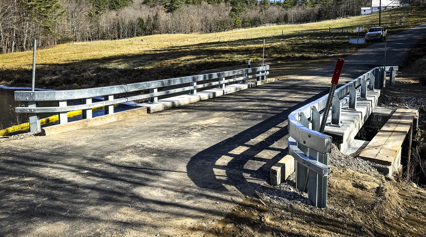 The completed Andover bridge pictured in sunlight with the focus on the new road and guardrails.