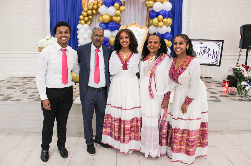 Rebekah posed with her family at a celebration. The women are in white dresses and the  men have pink ties.