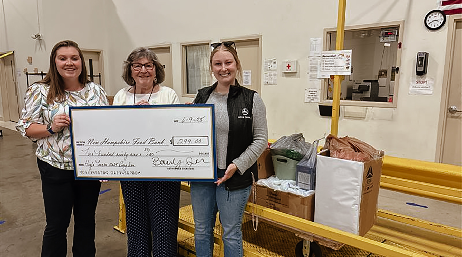 Bailey Jackson and Katie Welch are standing with a food bank representative holding a giant check for the charitable donation.