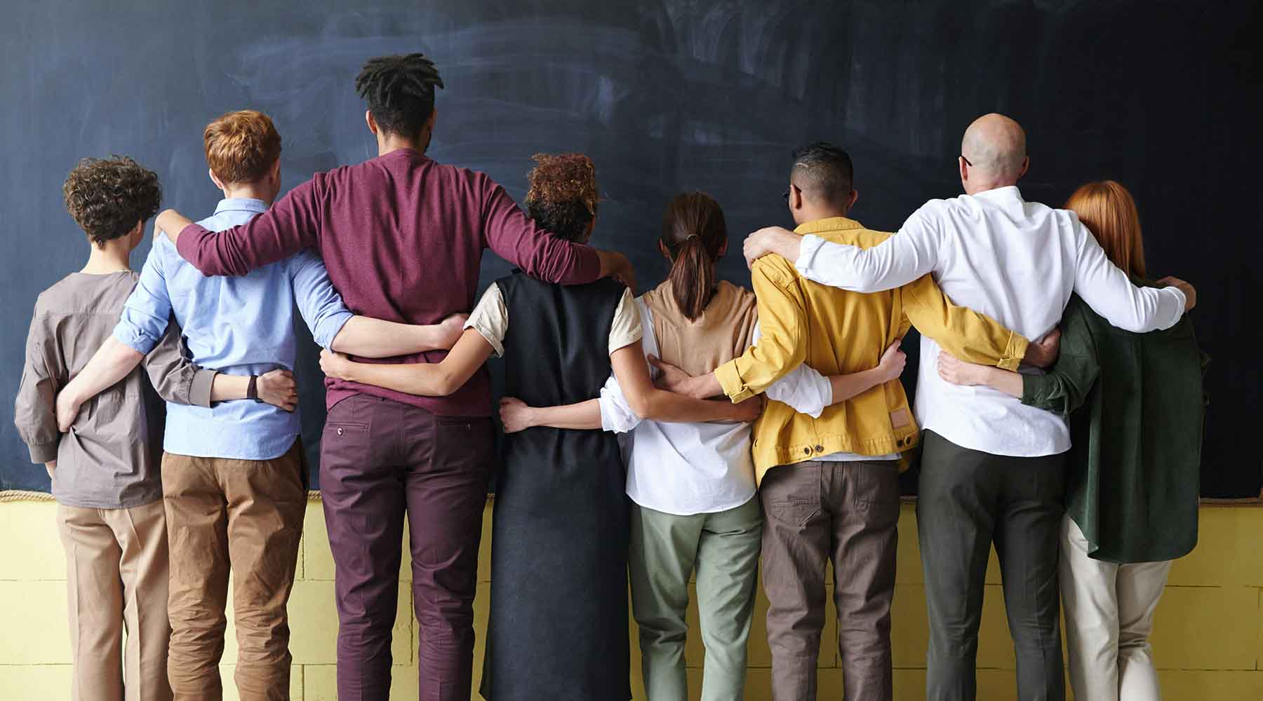 People linking arms, facing away from camera. 