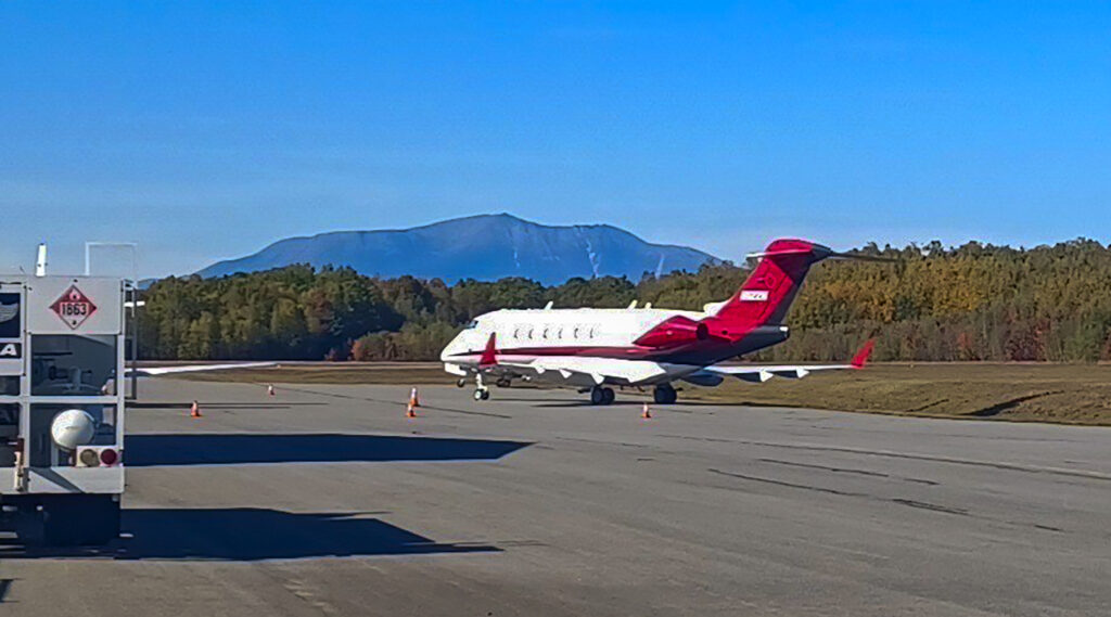 A plane sits on pavement at the airport. Mount Katahdin is in the background.