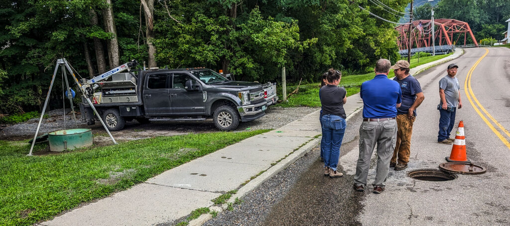 The team continues talking about the pump station project, while the bridge with the project utilities can be seen in the background.