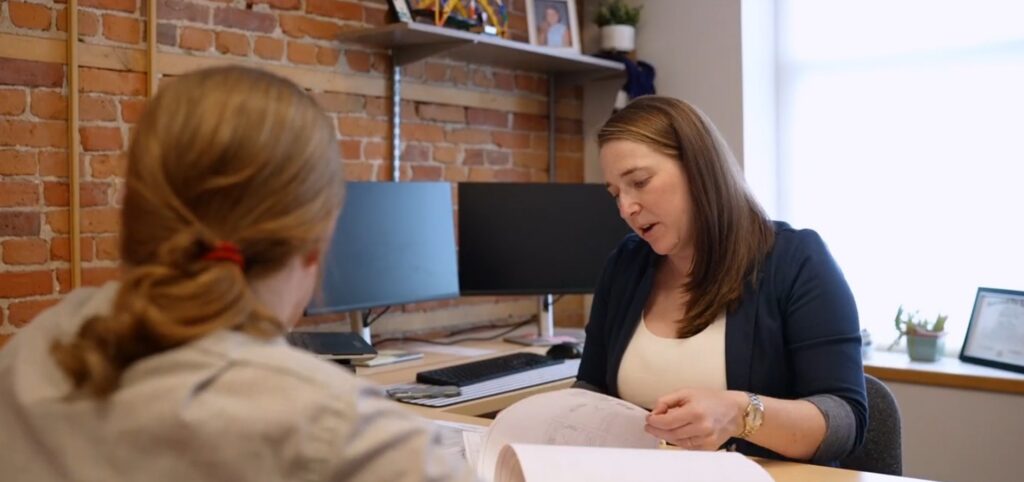 Kelly LaVigne and Zach sit together in the office reviewing documents