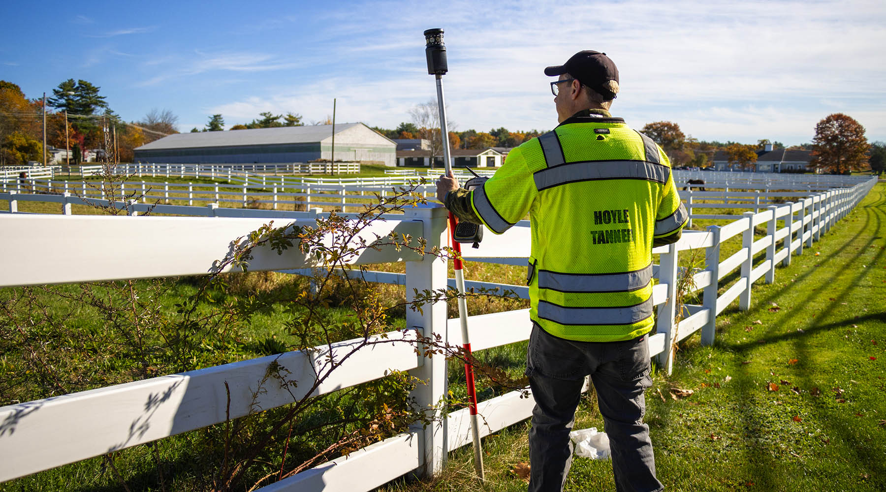 Dave Jeffery pictured surveying next to a long white fence on a sunny day.