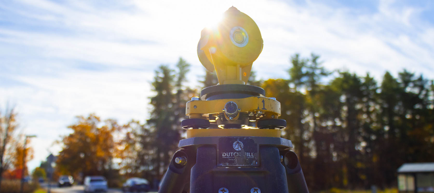 Survey equipment with fall trees in the background and sun shining down on the equipment.