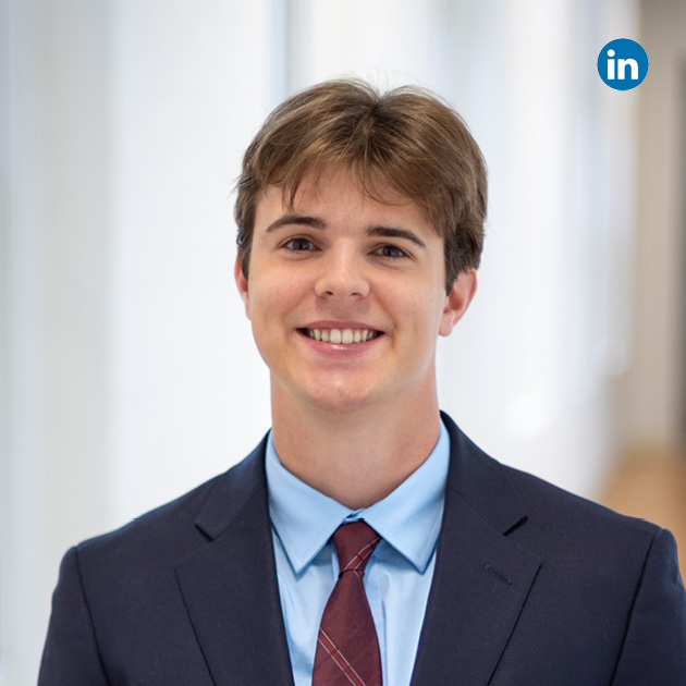 Jeremy Henault Headshot in a shirt, tie and suit coat smiling