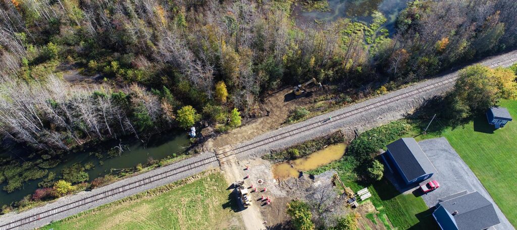 A photo of work in Van Buren with water bodies, a railroad, and equipment nearby.